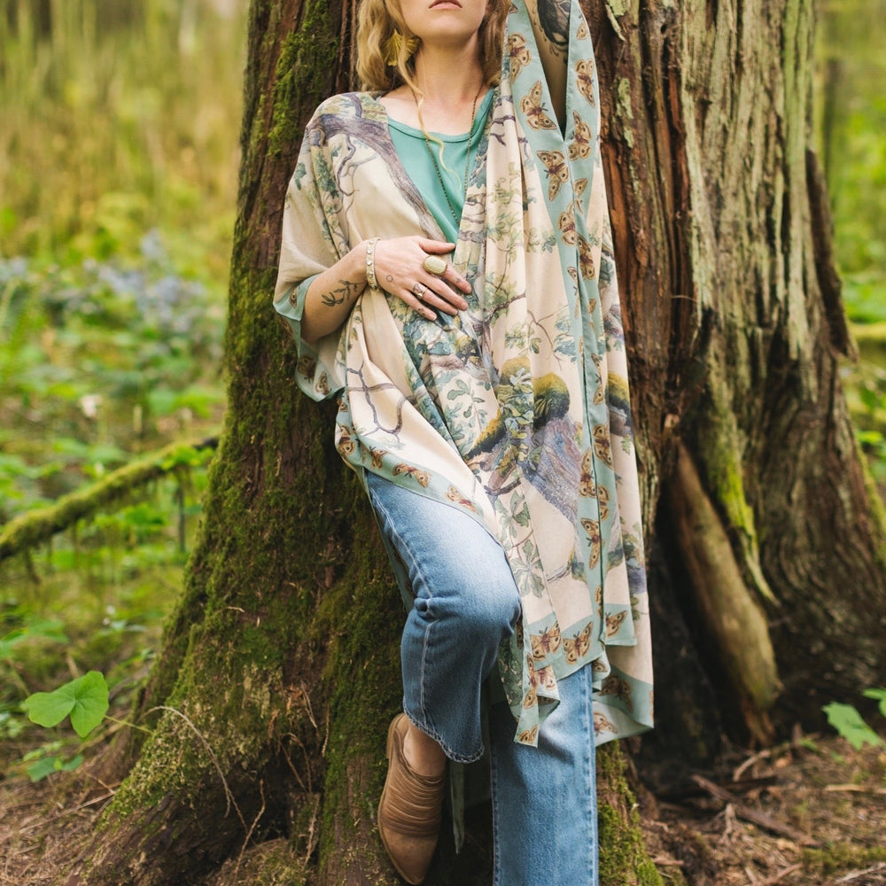 
                  
                    Model wearing the Earth and Sky Goddess length kimono featuring majestic trees by Charles Aston and antique moth illustrations – a dreamy tribute to nature – Market of Stars.
                  
                