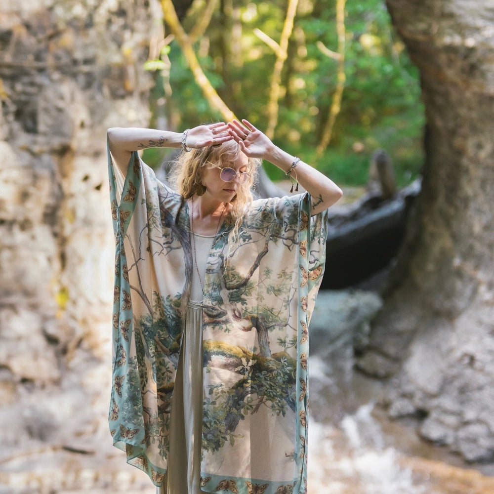 
                  
                    Model wearing the Earth and Sky Goddess length kimono featuring majestic trees by Charles Aston and antique moth illustrations – a dreamy tribute to nature – Market of Stars.
                  
                