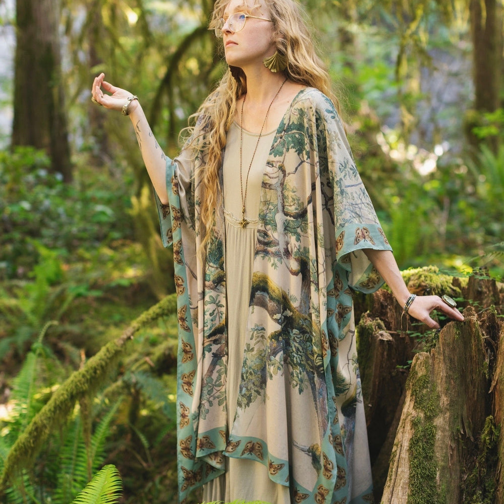 
                  
                    Model wearing the Earth and Sky Goddess length kimono featuring majestic trees by Charles Aston and antique moth illustrations – a dreamy tribute to nature – Market of Stars.
                  
                