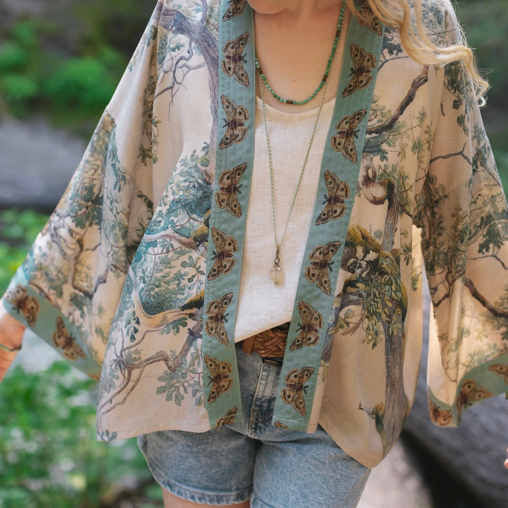 
                  
                    Model wearing Earth and Sky Pixie Duster featuring Charles Aston’s tree art and antique moth illustrations – a soft, nature-inspired layering piece – Market of Stars.
                  
                