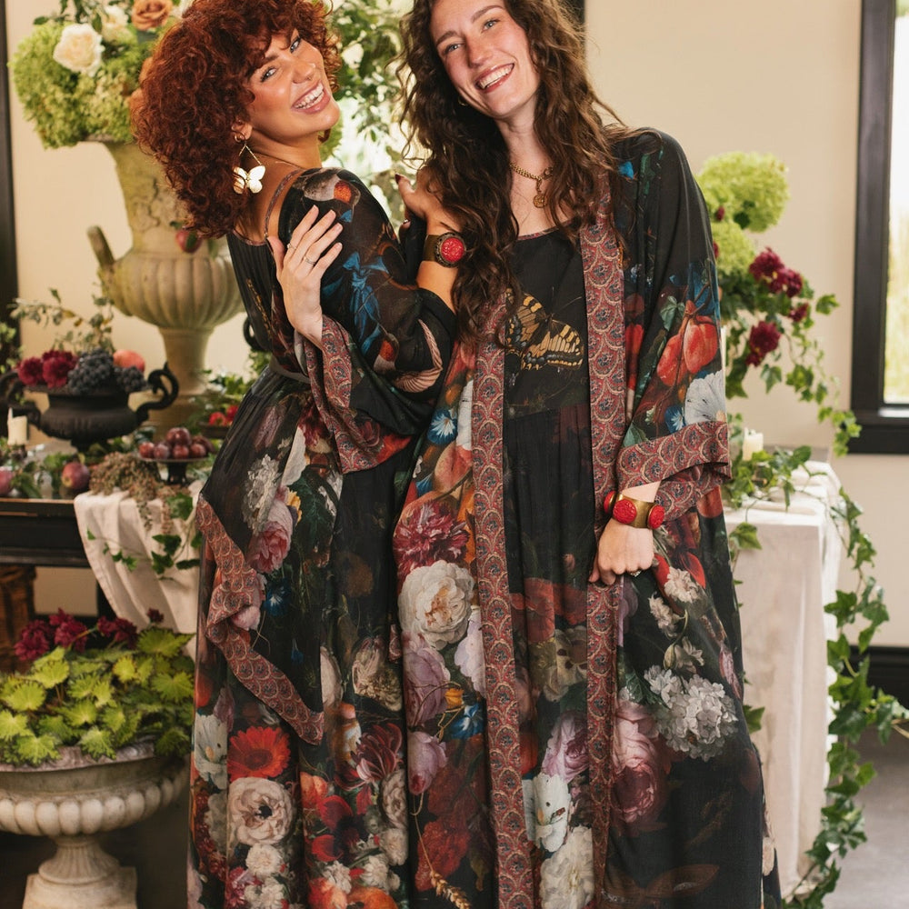 
                  
                    Model showcasing the Flight of Fancy Opera Robe featuring vibrant hummingbirds and historic floral paintings by Rachel Ruysch – Market of Stars.
                  
                