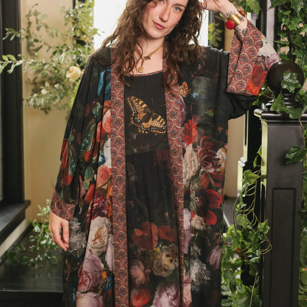 
                  
                    Model showcasing the Flight of Fancy Opera Robe featuring vibrant hummingbirds and historic floral paintings by Rachel Ruysch – Market of Stars.
                  
                