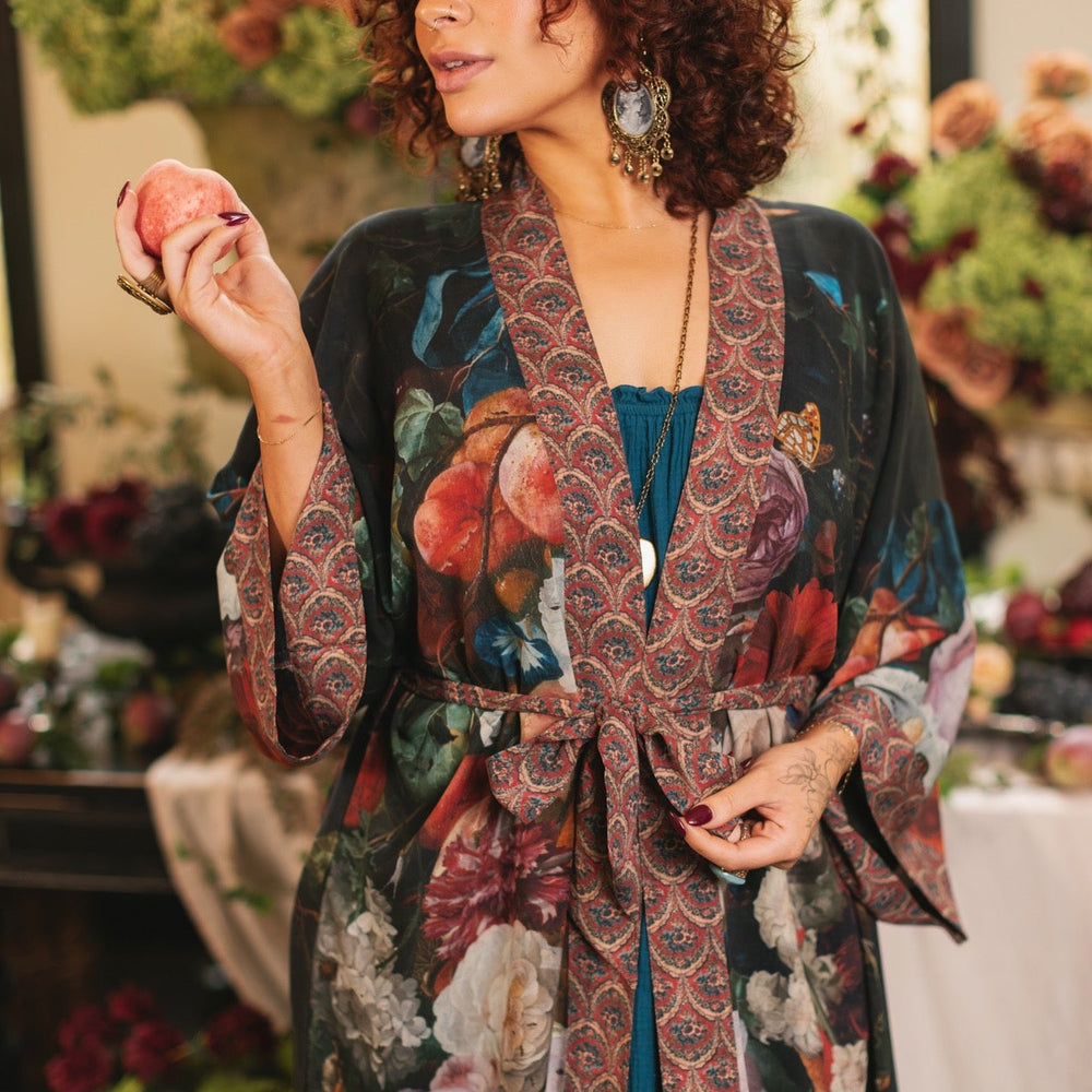 
                  
                    Model showcasing the Flight of Fancy Opera Robe featuring vibrant hummingbirds and historic floral paintings by Rachel Ruysch – Market of Stars.
                  
                