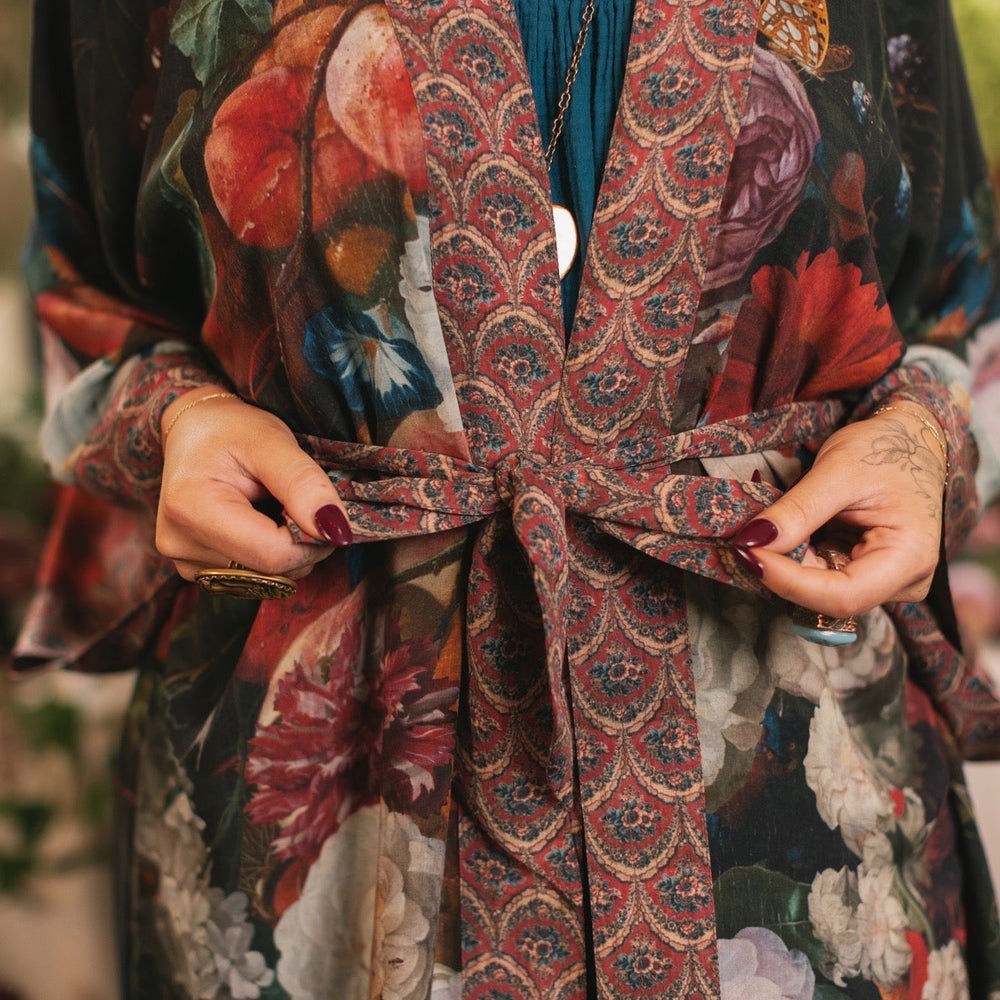 
                  
                    Model showcasing the Flight of Fancy Opera Robe featuring vibrant hummingbirds and historic floral paintings by Rachel Ruysch – Market of Stars.
                  
                