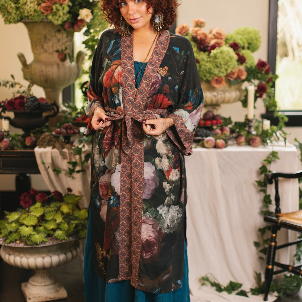 
                  
                    Model showcasing the Flight of Fancy Opera Robe featuring vibrant hummingbirds and historic floral paintings by Rachel Ruysch – Market of Stars.
                  
                