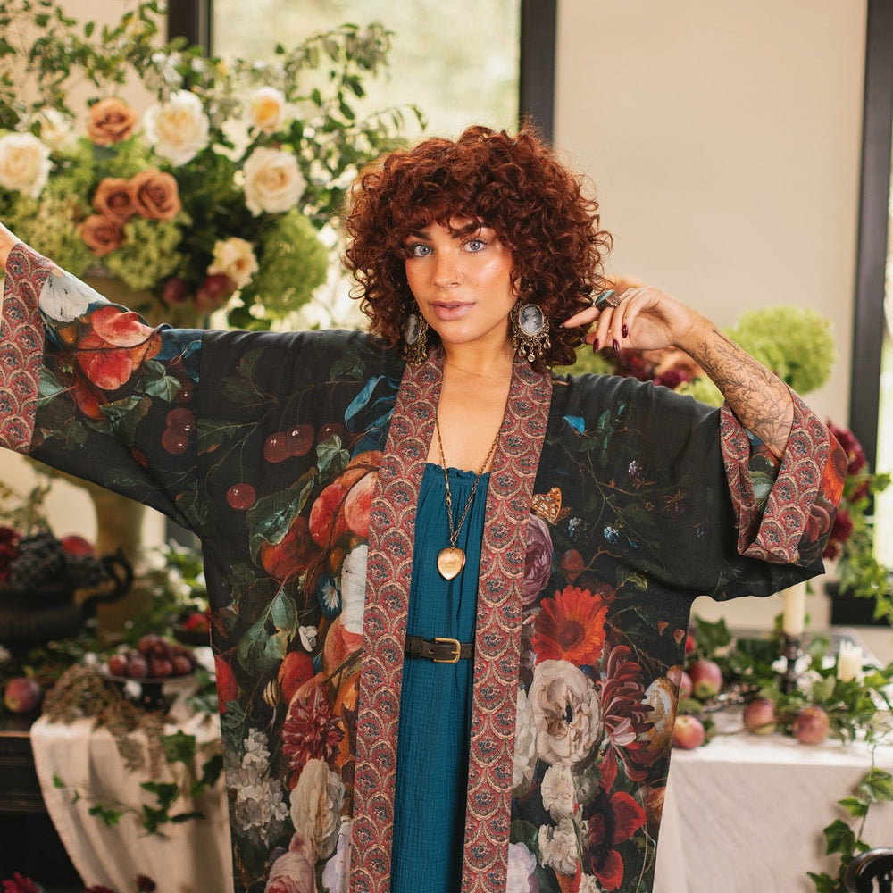 
                  
                    Model showcasing the Flight of Fancy Opera Robe featuring vibrant hummingbirds and historic floral paintings by Rachel Ruysch – Market of Stars.
                  
                