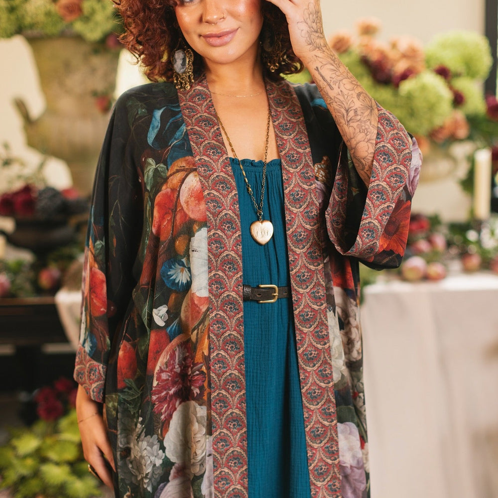 
                  
                    Model showcasing the Flight of Fancy Opera Robe featuring vibrant hummingbirds and historic floral paintings by Rachel Ruysch – Market of Stars.
                  
                