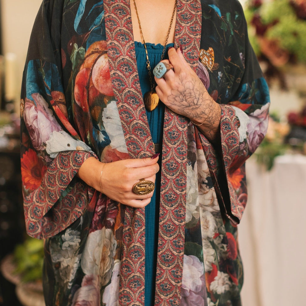 
                  
                    Model showcasing the Flight of Fancy Opera Robe featuring vibrant hummingbirds and historic floral paintings by Rachel Ruysch – Market of Stars.
                  
                