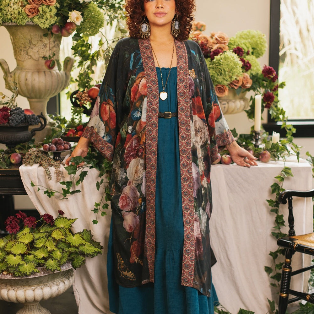 
                  
                    Model showcasing the Flight of Fancy Opera Robe featuring vibrant hummingbirds and historic floral paintings by Rachel Ruysch – Market of Stars.
                  
                
