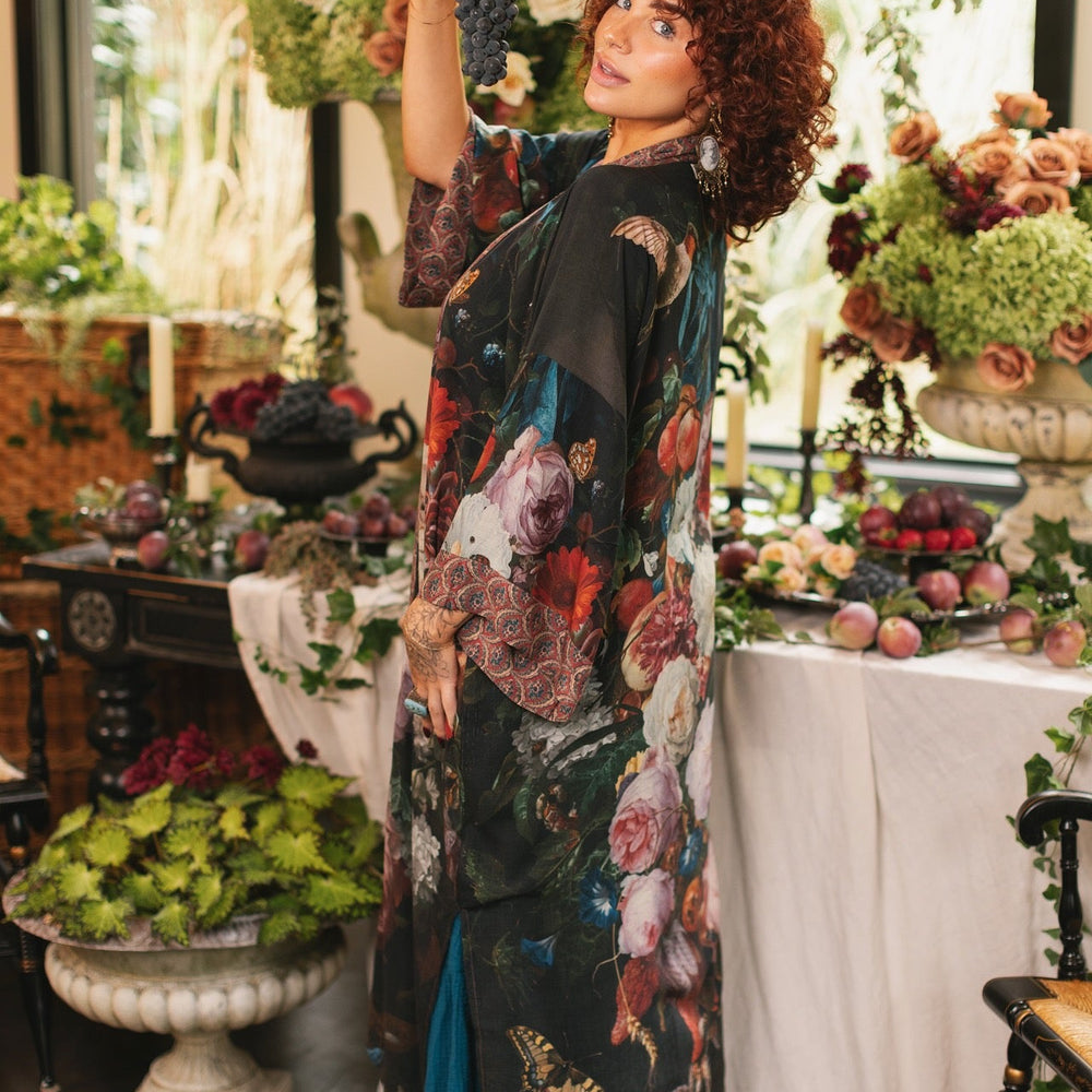 
                  
                    Model showcasing the Flight of Fancy Opera Robe featuring vibrant hummingbirds and historic floral paintings by Rachel Ruysch – Market of Stars.
                  
                