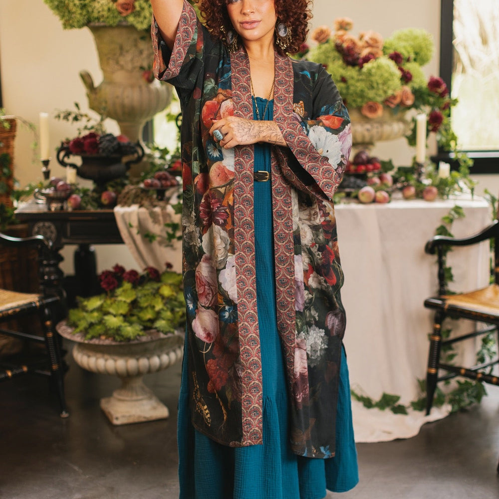 
                  
                    Model showcasing the Flight of Fancy Opera Robe featuring vibrant hummingbirds and historic floral paintings by Rachel Ruysch – Market of Stars.
                  
                