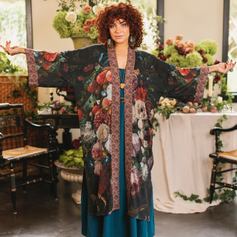 
                  
                    Model showcasing the Flight of Fancy Opera Robe featuring vibrant hummingbirds and historic floral paintings by Rachel Ruysch – Market of Stars.
                  
                