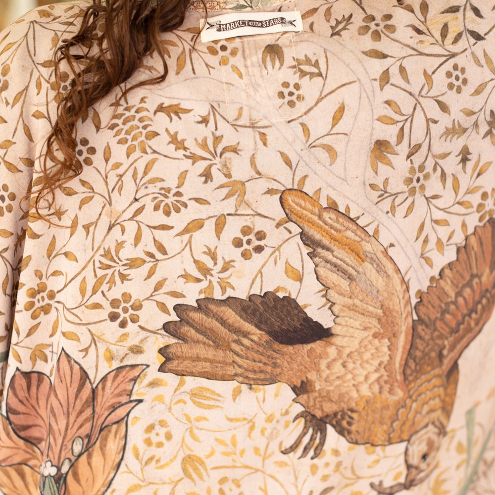
                  
                    Model wearing opera-length kimono featuring the embroidered Bird-of-Peace by Kim Donohoe and unfinished William Morris panels celebrating artistic process – Market of Stars.
                  
                