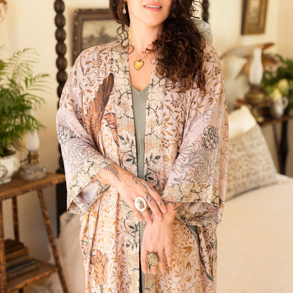 
                  
                    Model wearing opera-length kimono featuring the embroidered Bird-of-Peace by Kim Donohoe and unfinished William Morris panels celebrating artistic process – Market of Stars.
                  
                