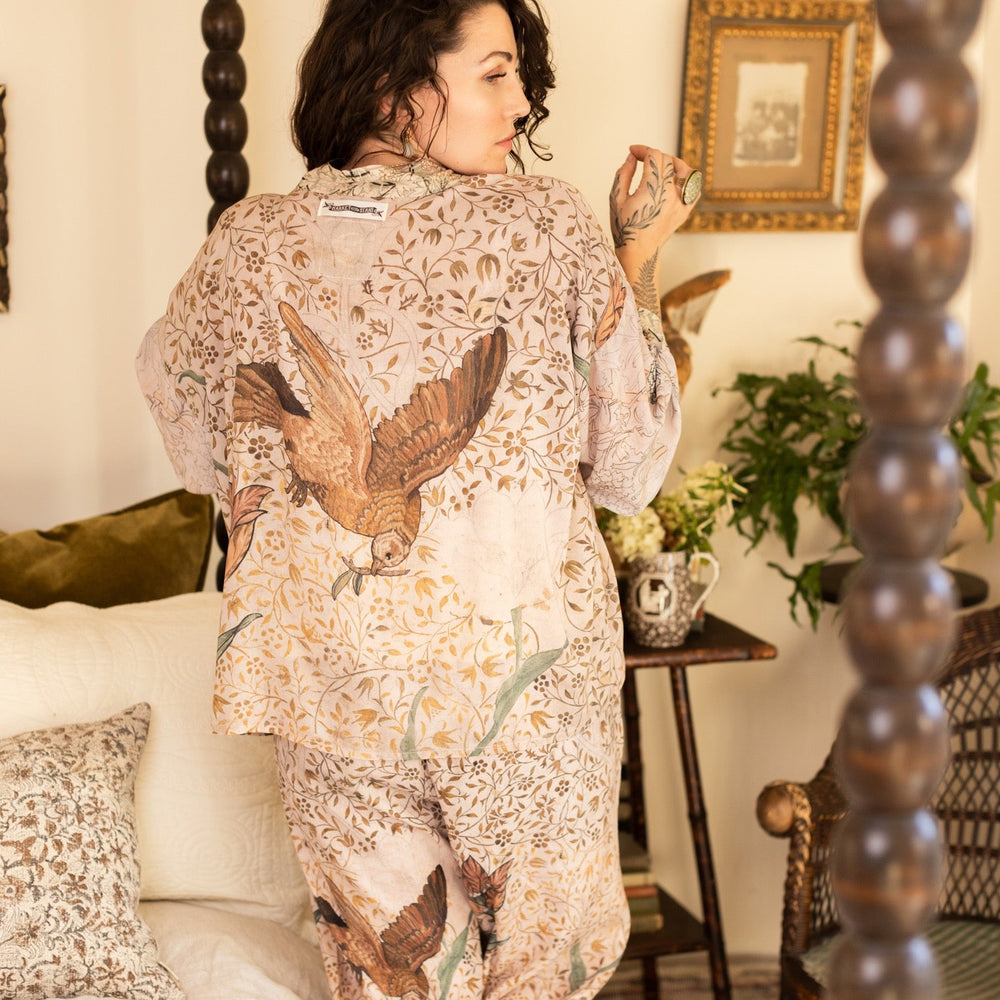 
                  
                    Model wearing full-length Folklore opera duster featuring Bird-of-Peace embroidery and unfinished William Morris textile panels in soft earthy tones – Market of Stars.
                  
                