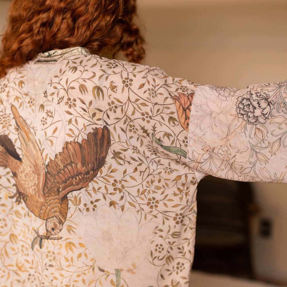 
                  
                    Model wearing full-length Folklore opera duster featuring Bird-of-Peace embroidery and unfinished William Morris textile panels in soft earthy tones – Market of Stars.
                  
                