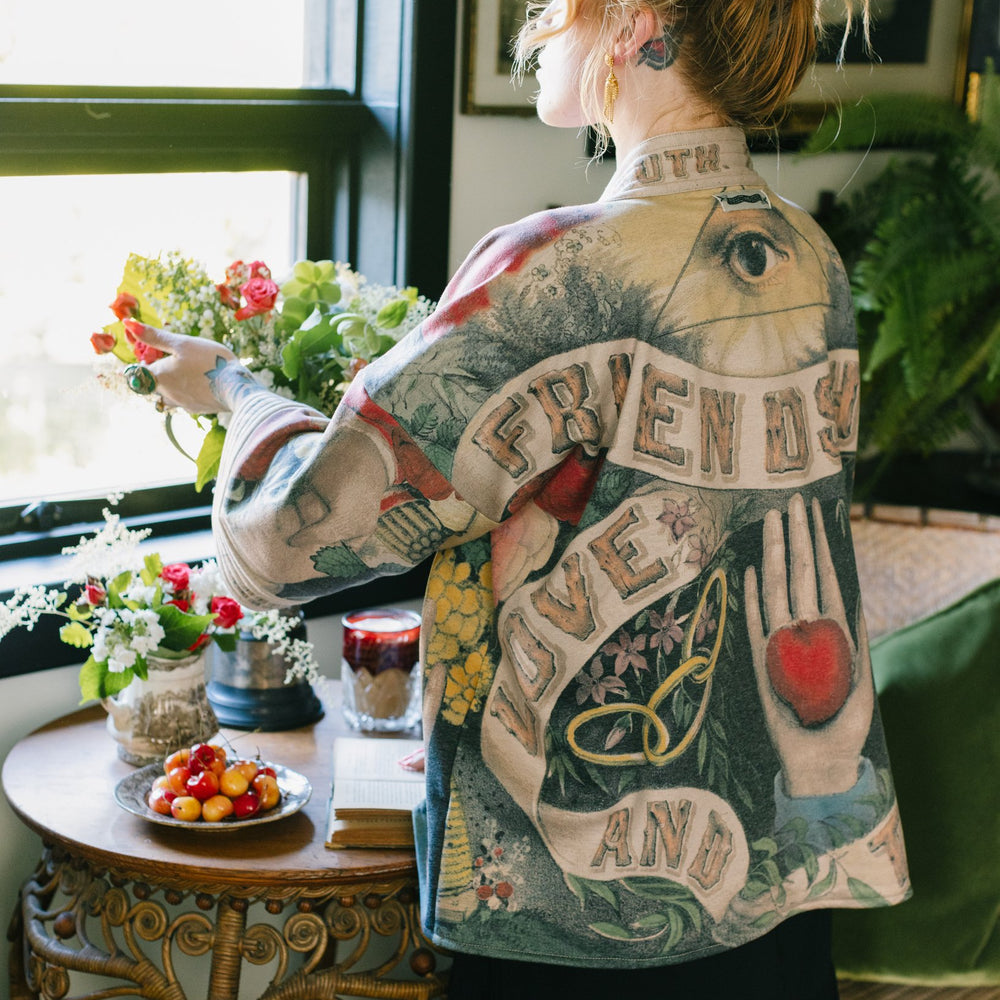 Model wearing cozy printed cardigan with vintage symbols of love, truth, and friendship, featuring charming wood-grain trim and patch pockets – Market of Stars.