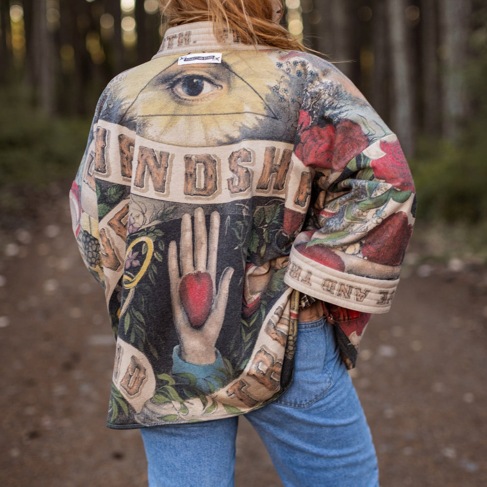 
                  
                    Model wearing cozy printed cardigan with vintage symbols of love, truth, and friendship, featuring charming wood-grain trim and patch pockets – Market of Stars.
                  
                