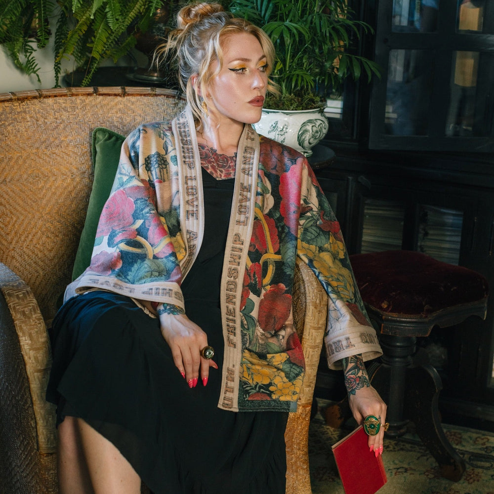 
                  
                    Model wearing cozy printed cardigan with vintage symbols of love, truth, and friendship, featuring charming wood-grain trim and patch pockets – Market of Stars.
                  
                