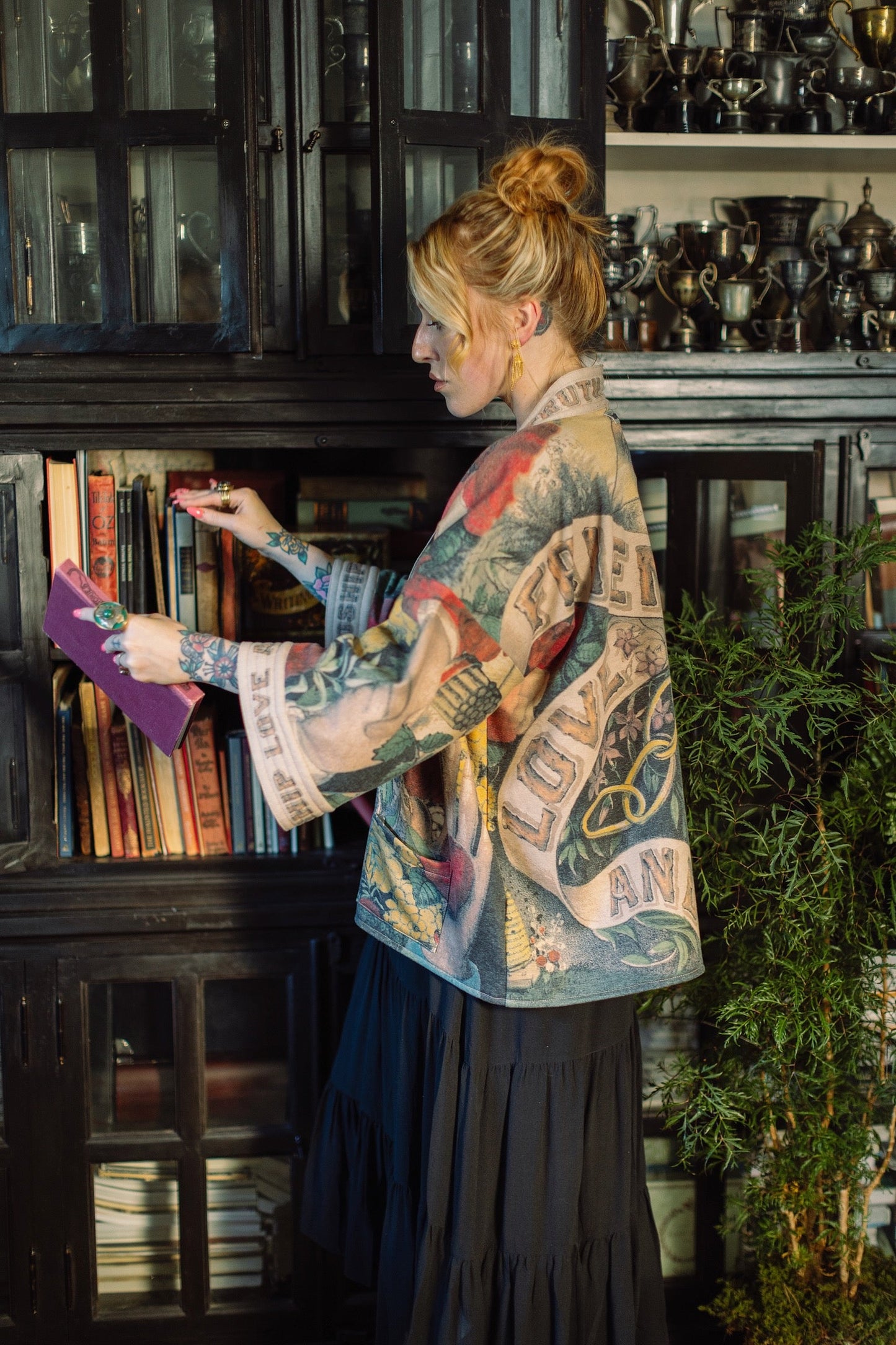 Model wearing cozy printed cardigan with vintage symbols of love, truth, and friendship, featuring charming wood-grain trim and patch pockets – Market of Stars.