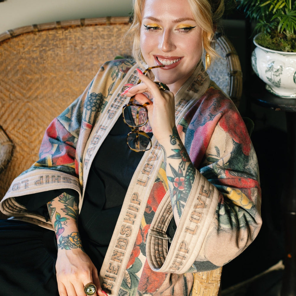 
                  
                    Model wearing cozy printed cardigan with vintage symbols of love, truth, and friendship, featuring charming wood-grain trim and patch pockets – Market of Stars.
                  
                