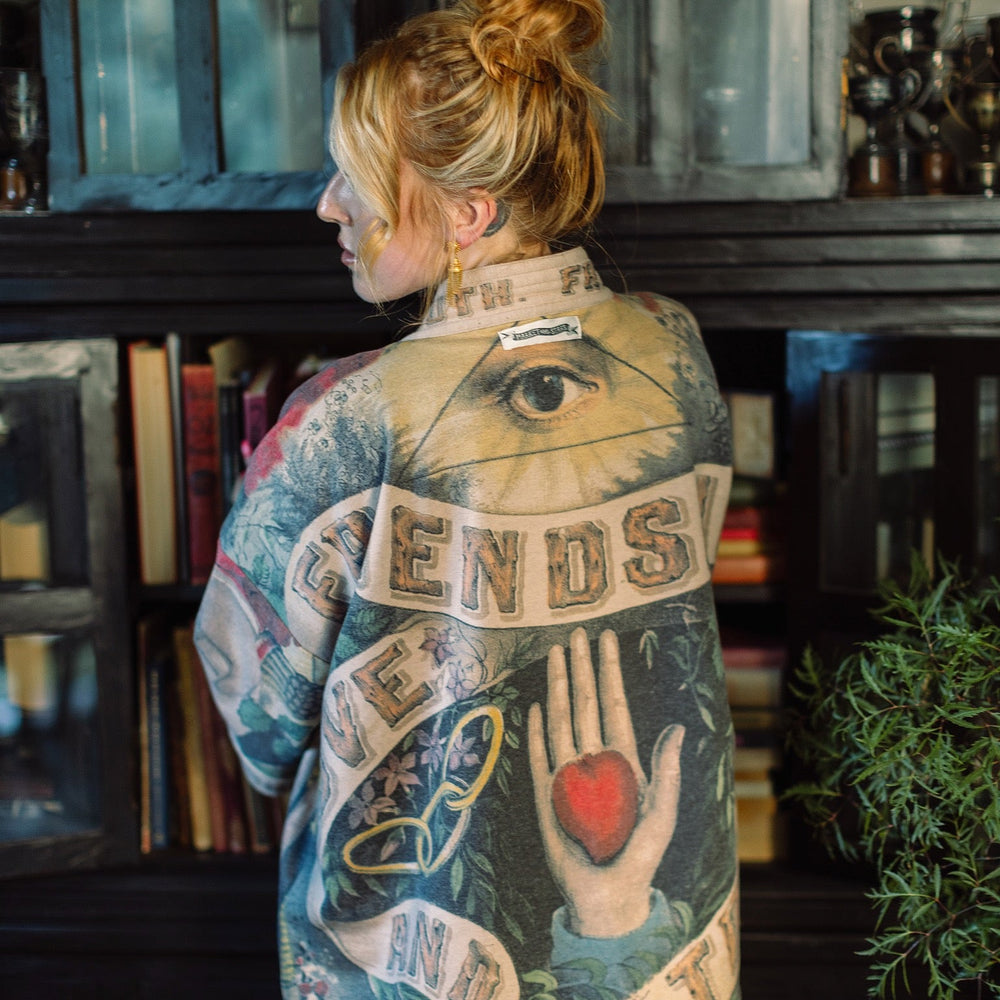 
                  
                    Model wearing cozy printed cardigan with vintage symbols of love, truth, and friendship, featuring charming wood-grain trim and patch pockets – Market of Stars.
                  
                