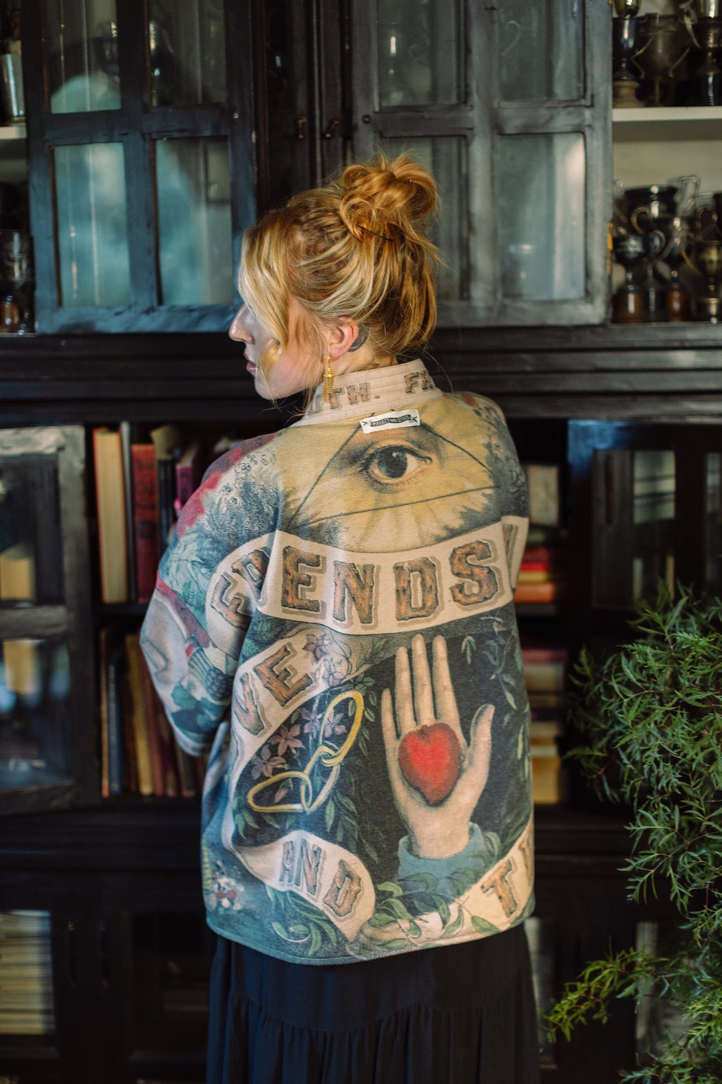 Model wearing cozy printed cardigan with vintage symbols of love, truth, and friendship, featuring charming wood-grain trim and patch pockets – Market of Stars.