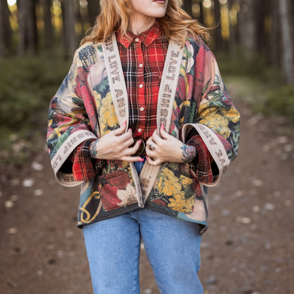 
                  
                    Model wearing cozy printed cardigan with vintage symbols of love, truth, and friendship, featuring charming wood-grain trim and patch pockets – Market of Stars.
                  
                