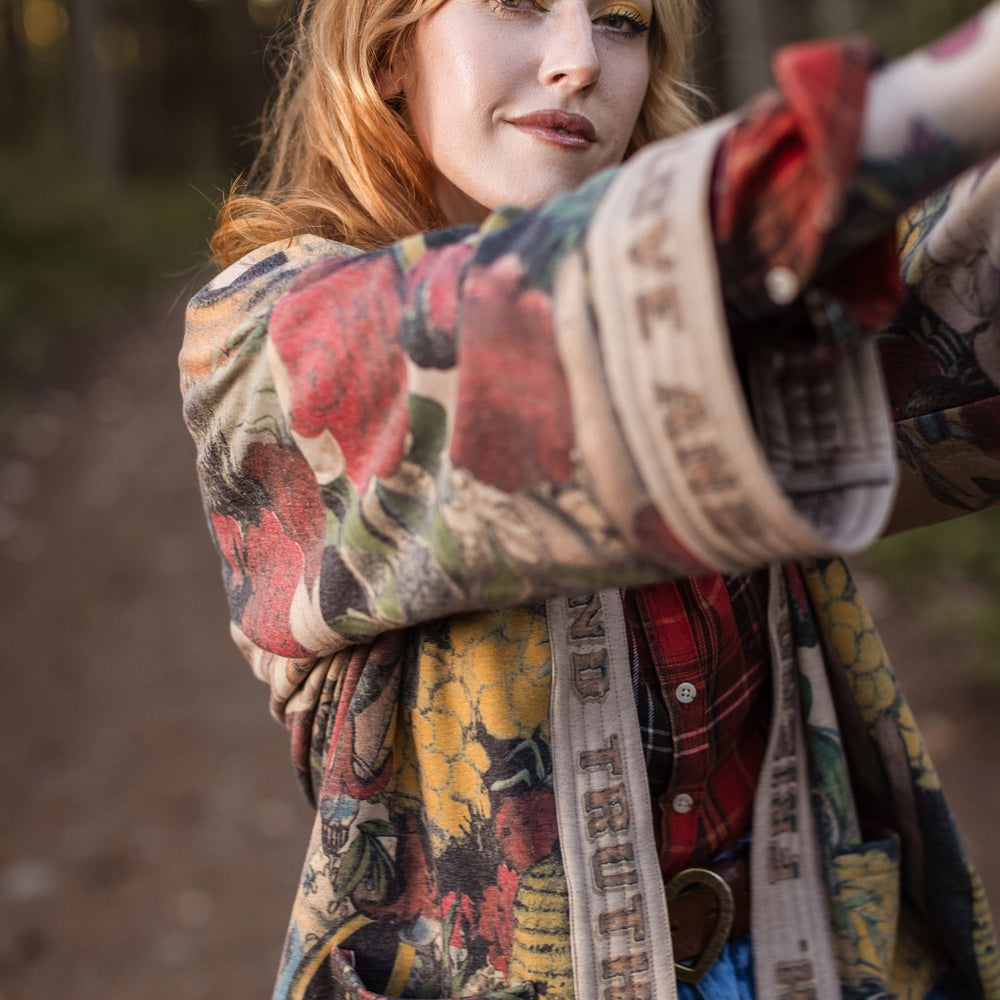 
                  
                    Model wearing cozy printed cardigan with vintage symbols of love, truth, and friendship, featuring charming wood-grain trim and patch pockets – Market of Stars.
                  
                