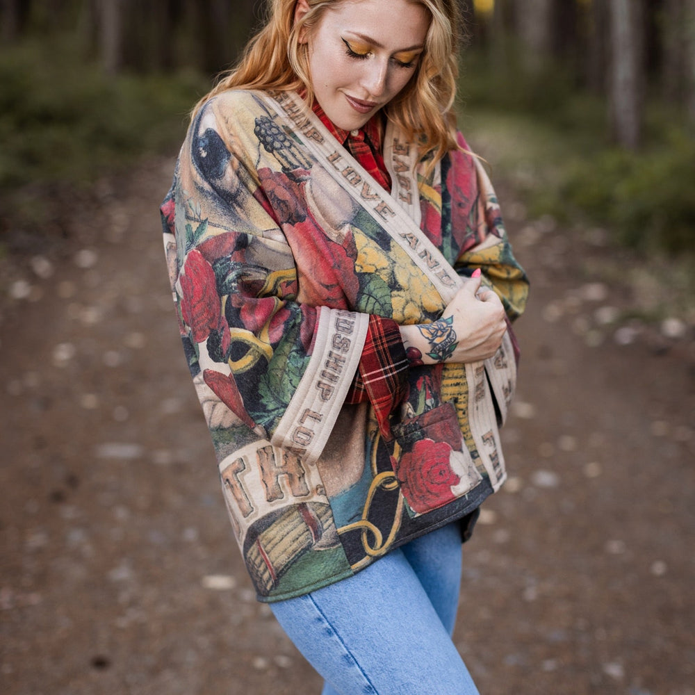 
                  
                    Model wearing cozy printed cardigan with vintage symbols of love, truth, and friendship, featuring charming wood-grain trim and patch pockets – Market of Stars.
                  
                