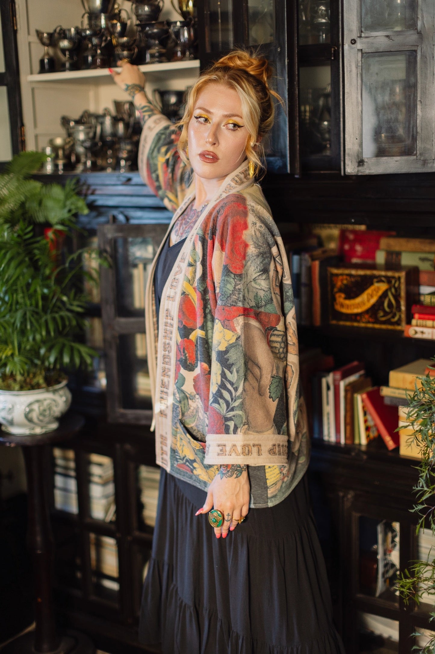 Model wearing cozy printed cardigan with vintage symbols of love, truth, and friendship, featuring charming wood-grain trim and patch pockets – Market of Stars.