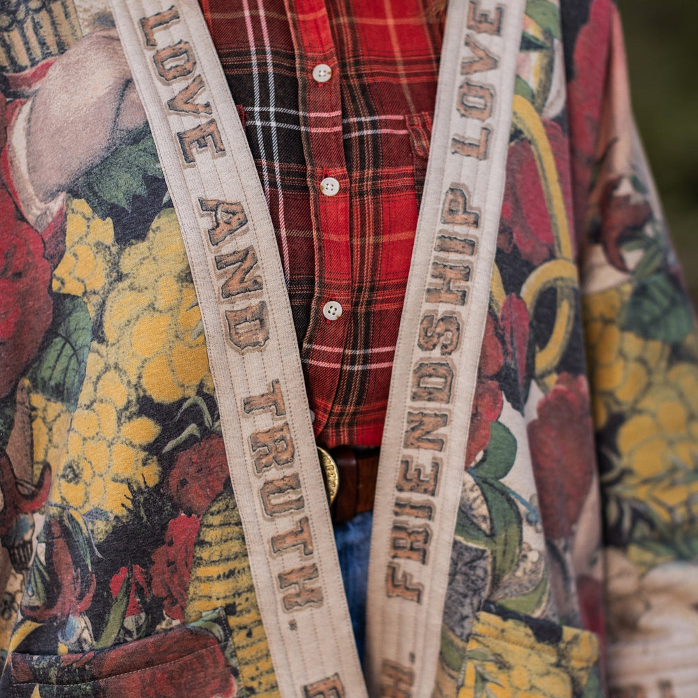 
                  
                    Model wearing cozy printed cardigan with vintage symbols of love, truth, and friendship, featuring charming wood-grain trim and patch pockets – Market of Stars.
                  
                