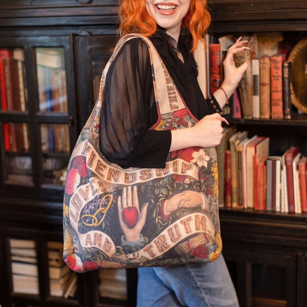 Model holding Friendship Love and Truth tote featuring historic symbols of cooperation, teamwork, eternal love, and truth from an 1880s print – Market of Stars.