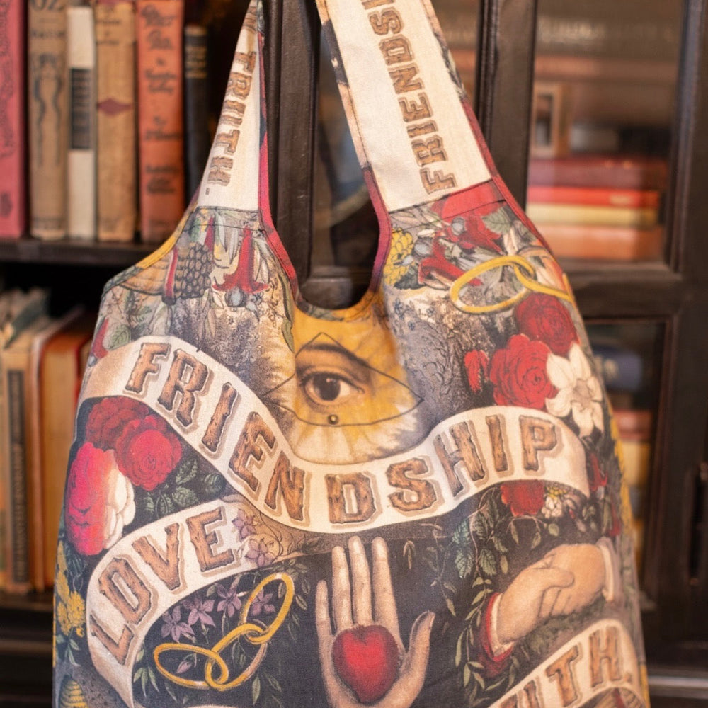 Model holding Friendship Love and Truth tote featuring historic symbols of cooperation, teamwork, eternal love, and truth from an 1880s print – Market of Stars.