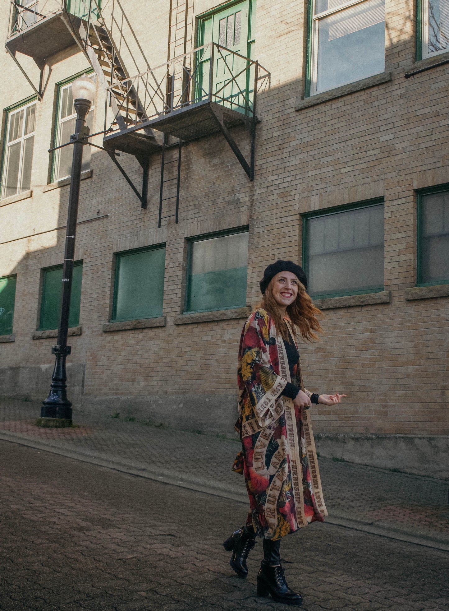 Model wearing our long, eclectic opera duster featuring vintage symbols of love, kindness, and truth in a bold archive-inspired print with removable belt – Market of Stars.