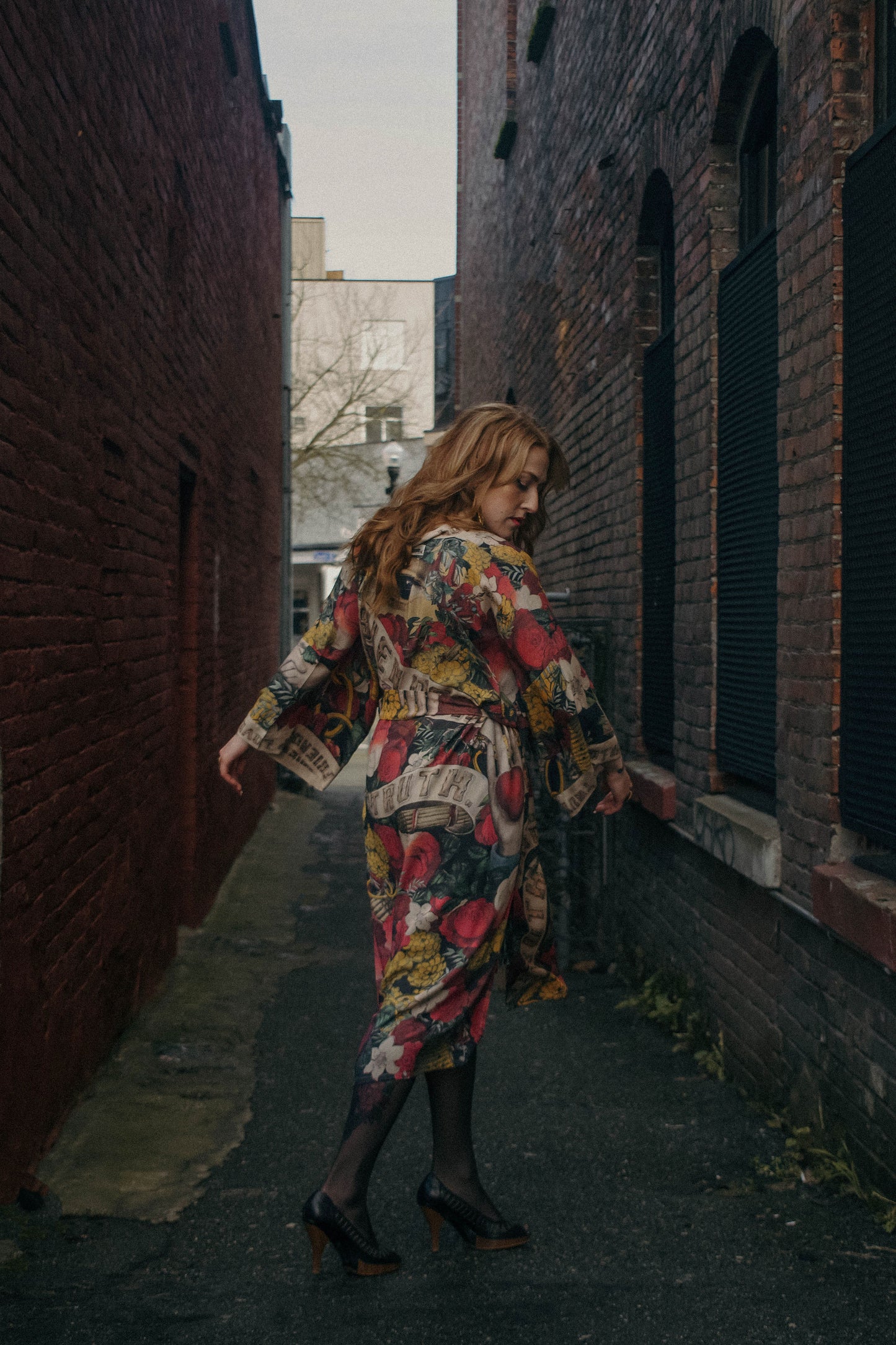 Model wearing our long, eclectic opera duster featuring vintage symbols of love, kindness, and truth in a bold archive-inspired print with removable belt – Market of Stars.