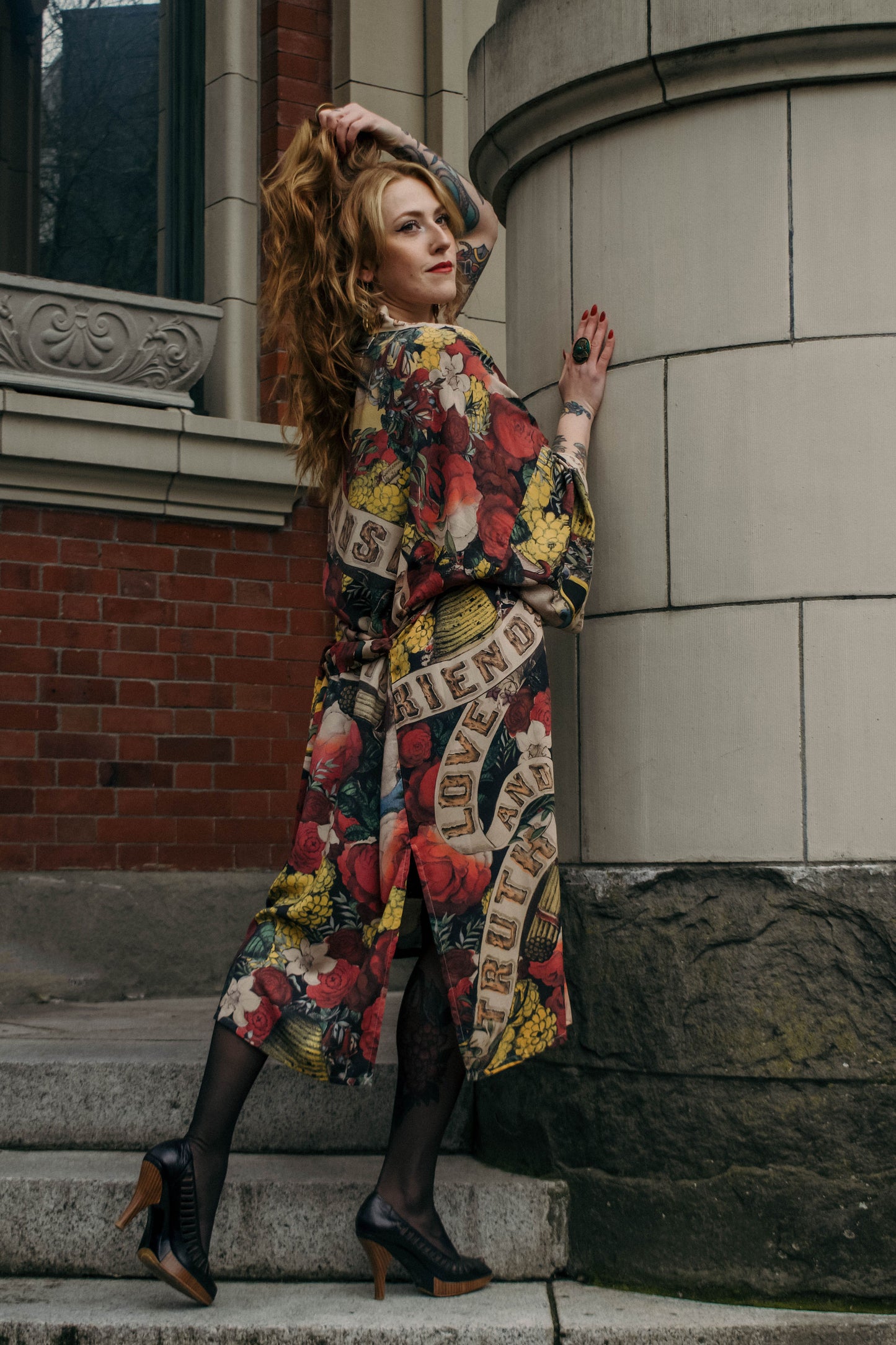 Model wearing our long, eclectic opera duster featuring vintage symbols of love, kindness, and truth in a bold archive-inspired print with removable belt – Market of Stars.