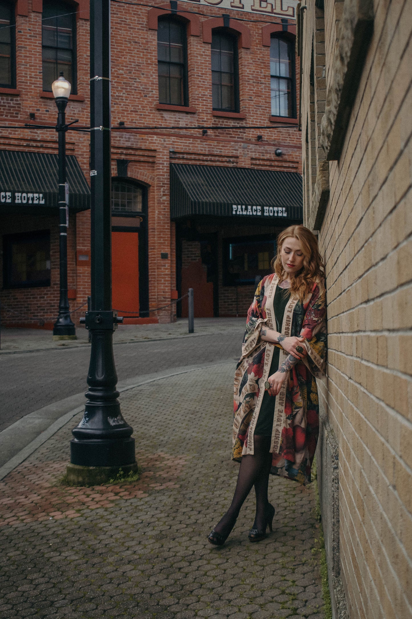 Model wearing our long, eclectic opera duster featuring vintage symbols of love, kindness, and truth in a bold archive-inspired print with removable belt – Market of Stars.