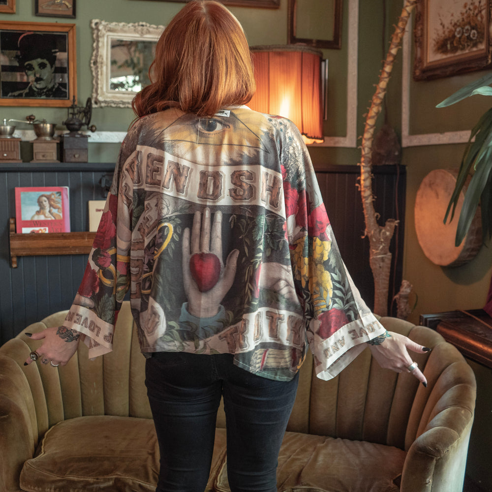 
                  
                    Model wearing our cropped kimono featuring historic symbols of friendship, love, and truth with archive-inspired wood-grain trim and romantic vintage details – Market of Stars.
                  
                