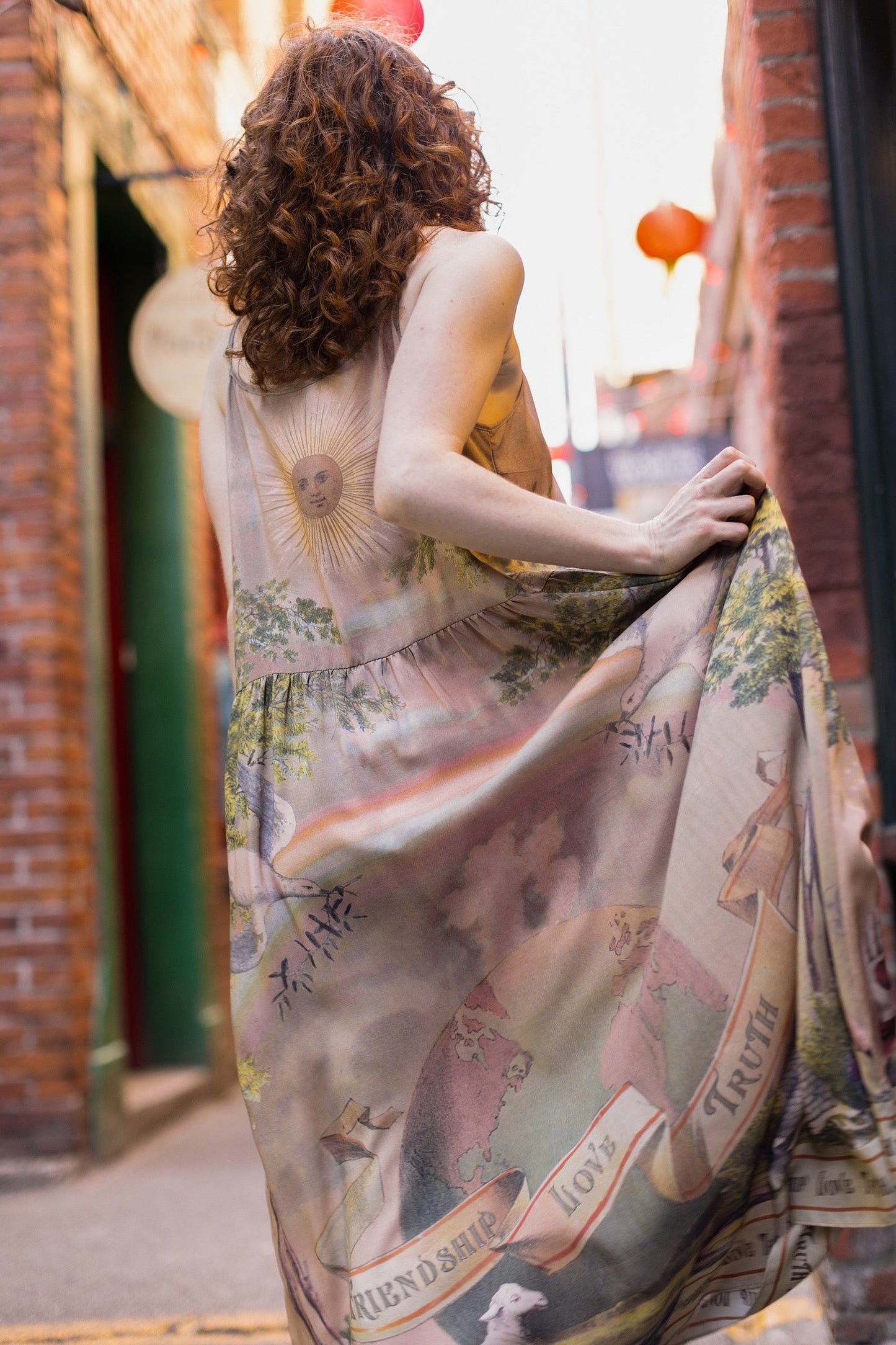 Model wearing sun-washed Bohéme slip dress featuring historic symbols of friendship, love, and truth in soft lavender, sage, gold, and aqua – Market of Stars.