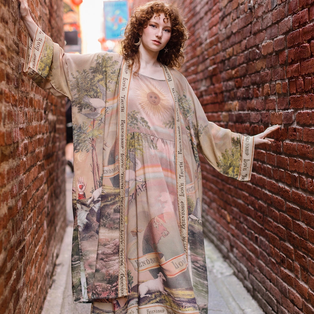 
                  
                    Model wearing sun-washed Bohéme slip dress featuring historic symbols of friendship, love, and truth in soft lavender, sage, gold, and aqua – Market of Stars.
                  
                
