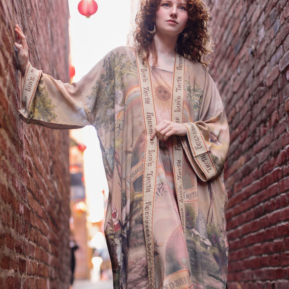 
                  
                    Model wearing sun-washed vintage-inspired Opera Duster featuring symbols of friendship, love, and truth in soft lavender, sage, gold, and aqua – Market of Stars
                  
                