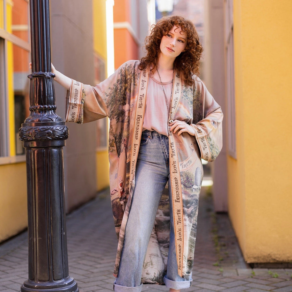
                  
                    Model wearing sun-washed vintage-inspired Opera Duster featuring symbols of friendship, love, and truth in soft lavender, sage, gold, and aqua – Market of Stars
                  
                