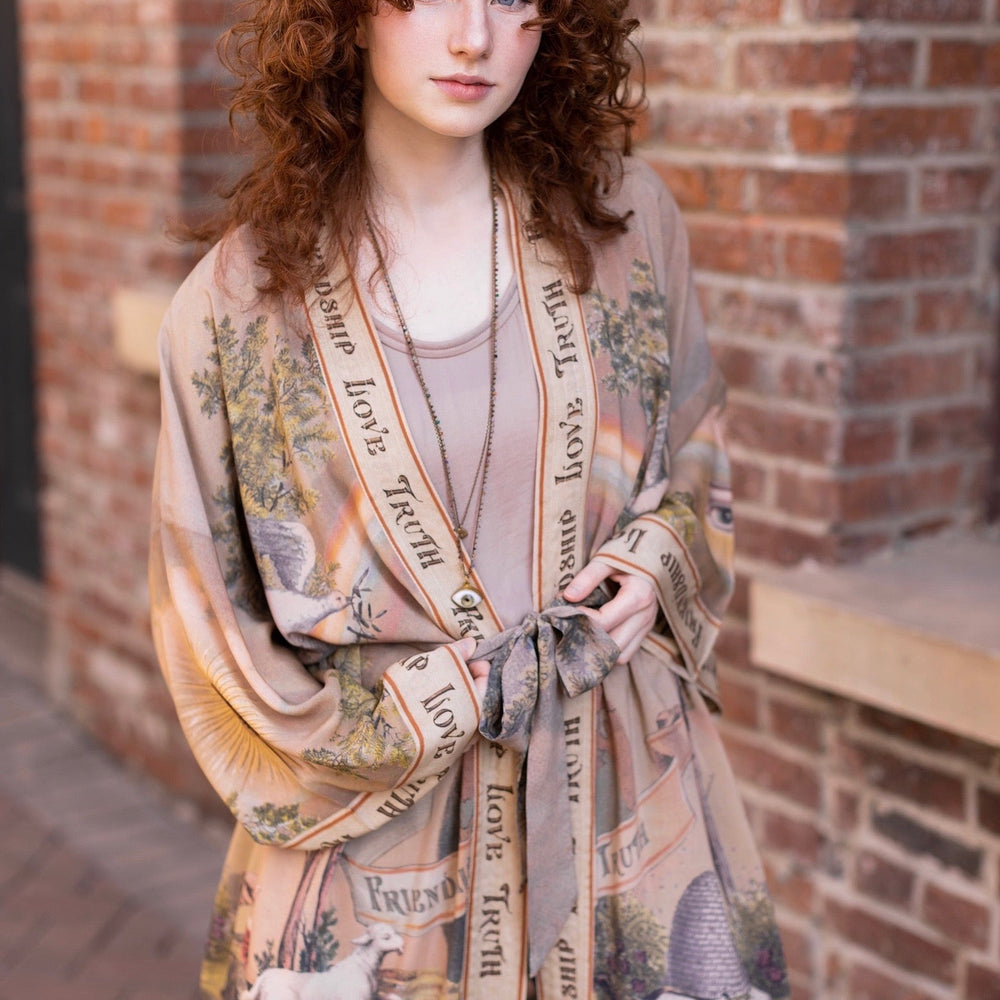 
                  
                    Model wearing sun-washed vintage-inspired Opera Duster featuring symbols of friendship, love, and truth in soft lavender, sage, gold, and aqua – Market of Stars
                  
                