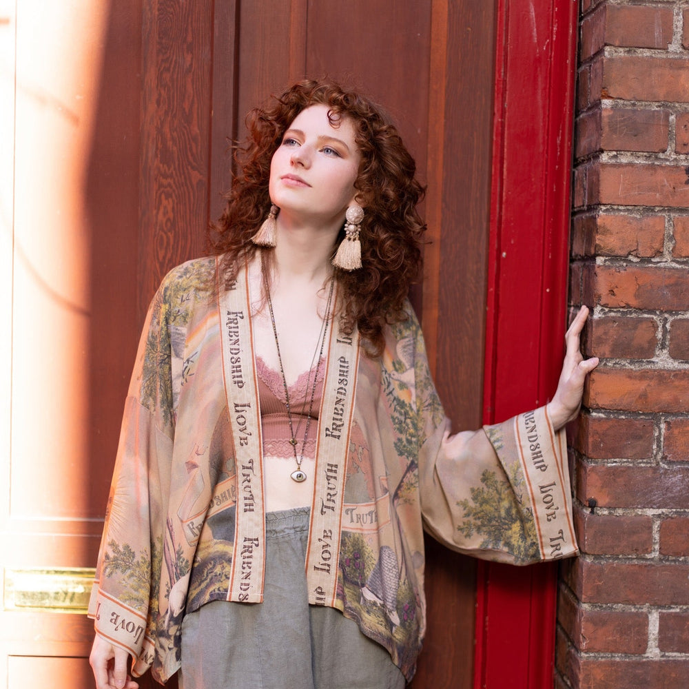 
                  
                    Vintage-inspired cropped kimono featuring historic symbols of friendship, love, and truth in a soft sun-washed palette of lavender, sage, gold, and aqua – Market of Stars.
                  
                