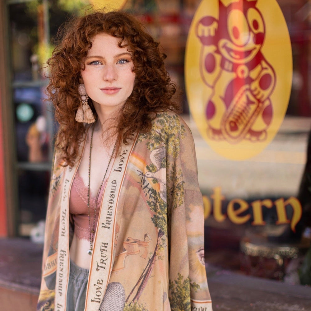 
                  
                    Vintage-inspired cropped kimono featuring historic symbols of friendship, love, and truth in a soft sun-washed palette of lavender, sage, gold, and aqua – Market of Stars.
                  
                