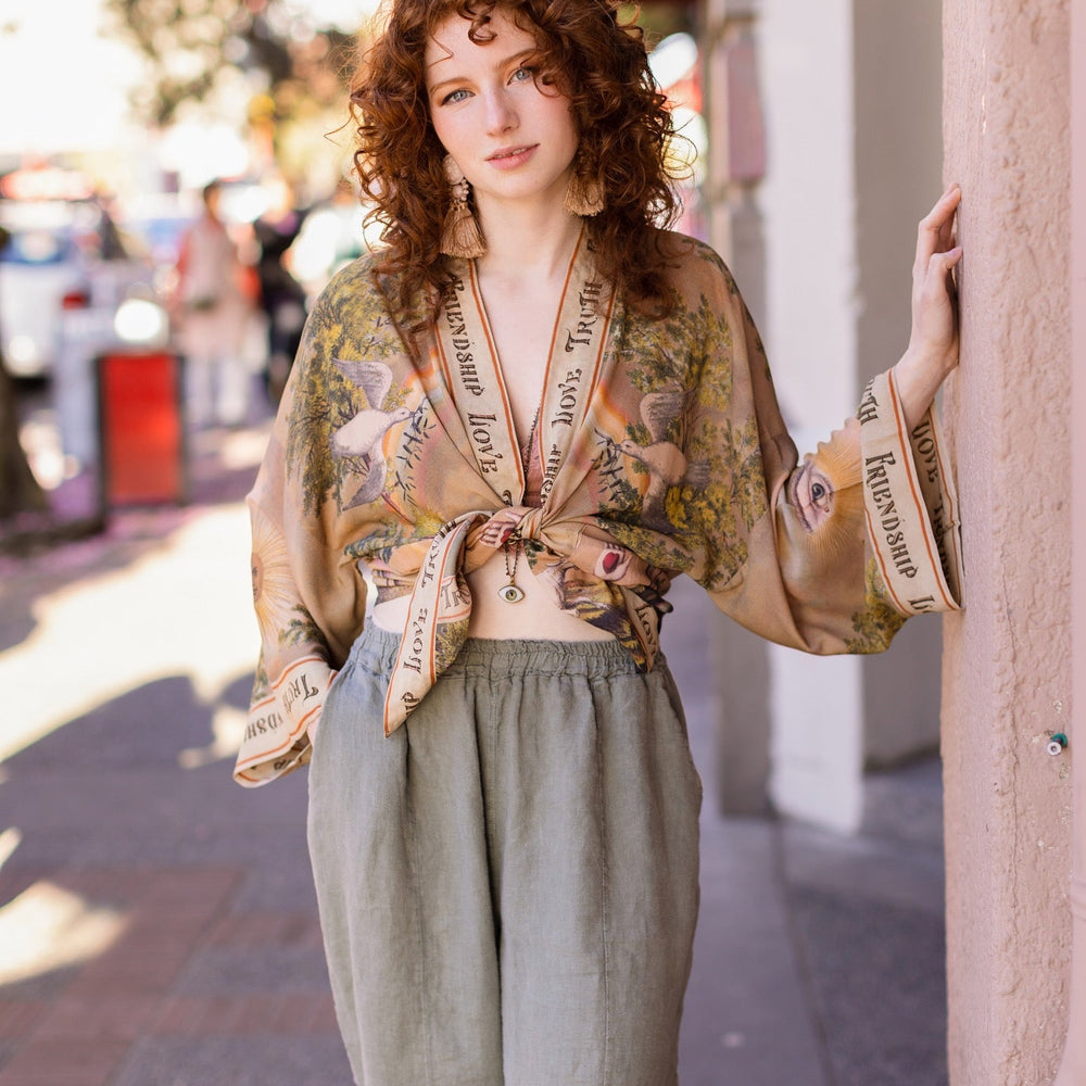 
                  
                    Vintage-inspired cropped kimono featuring historic symbols of friendship, love, and truth in a soft sun-washed palette of lavender, sage, gold, and aqua – Market of Stars.
                  
                