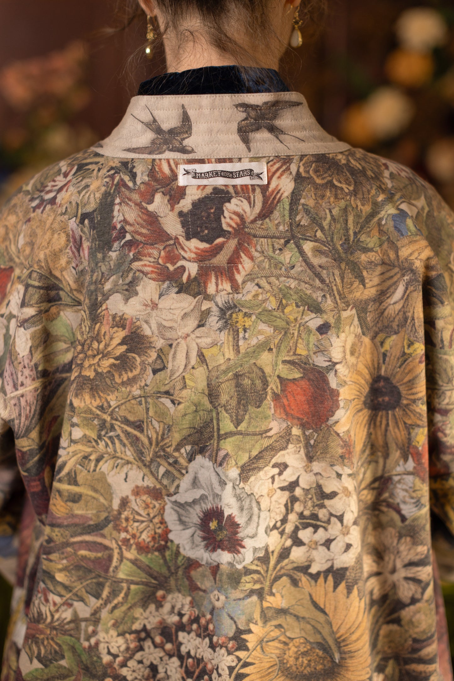 Model wearing a soft fleece cottage cardigan featuring rich 1700s botanical blooms and swallow trim - Market of Stars