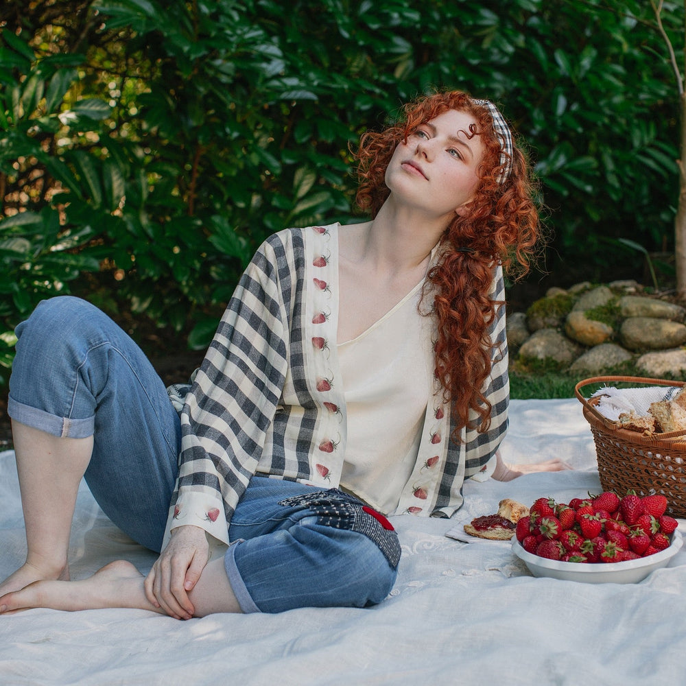
                  
                    Model wearing Happy Days pixie cut kimono featuring heritage gingham, vintage strawberries, and a cross-stitch patch inspired by an 1836 sampler – Market of Stars.
                  
                