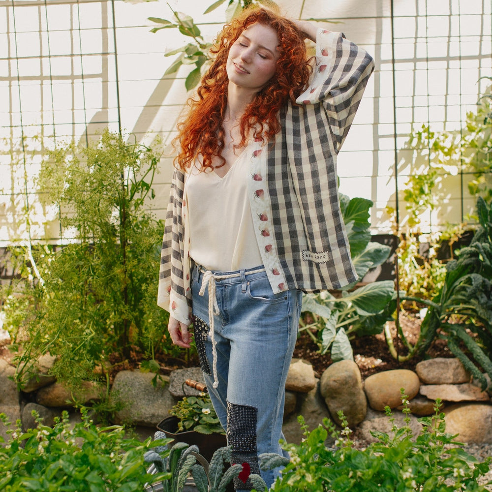 
                  
                    Model wearing Happy Days pixie cut kimono featuring heritage gingham, vintage strawberries, and a cross-stitch patch inspired by an 1836 sampler – Market of Stars.
                  
                